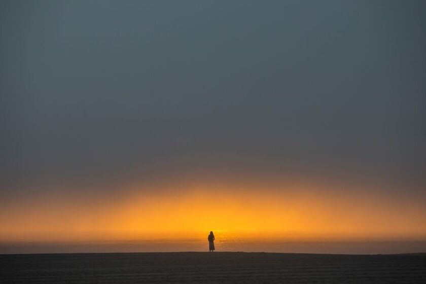 TOPSHOT - A woman watches the sunset from the beach in Venice, California on April 26, 2020. - Los Angeles County beaches are still off limits under Los Angeles countys "Safer at Home" order scheduled to be enforced through at least May 15 amid the novel coronavirus pandemic. (Photo by Apu GOMES / AFP) (Photo by APU GOMES/AFP via Getty Images)