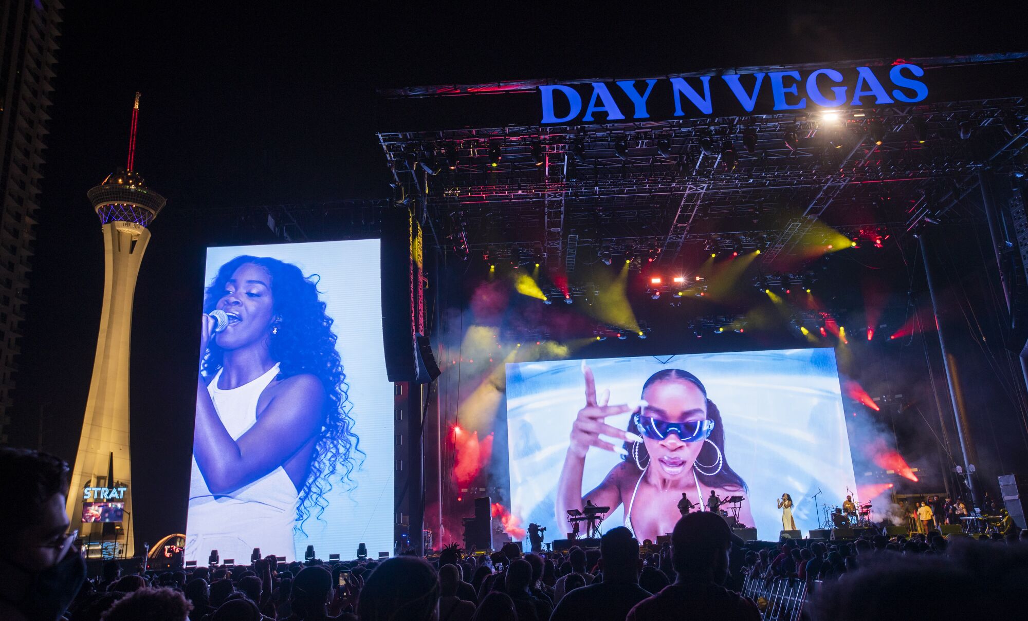Ari Lennox performs with large screens behind the stage showing performers singing.