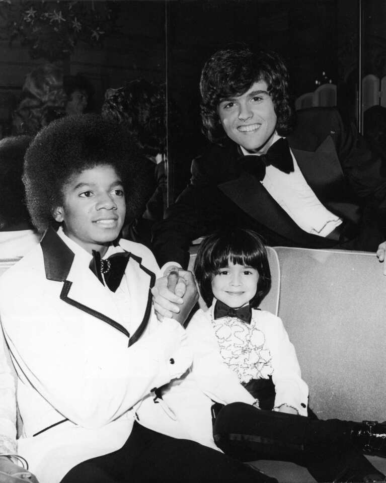 Michael Jackson in an oversized bow tie, left, and Donny Osmond pose with child actor Ricky Segall in 1974.