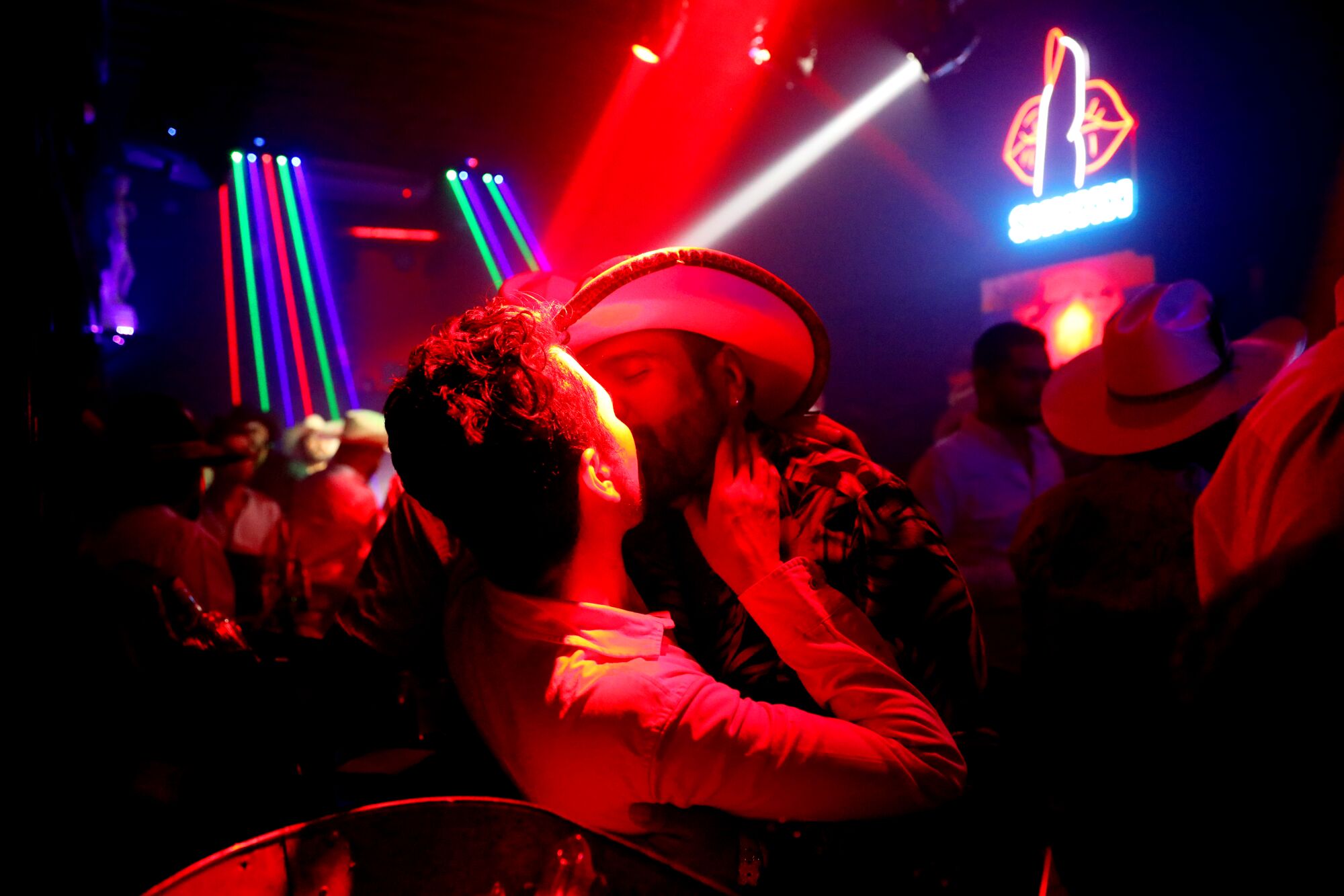 Men kiss under club lights.