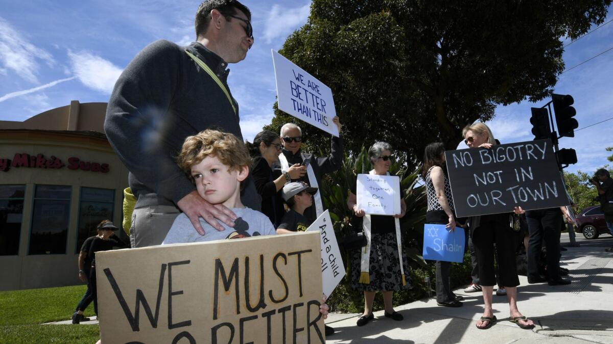 Kyle Fox holds a sign with his father, Brady Fox, in April in support of the victims of the Chabad of Poway synagogue shooting in Poway, Calif.