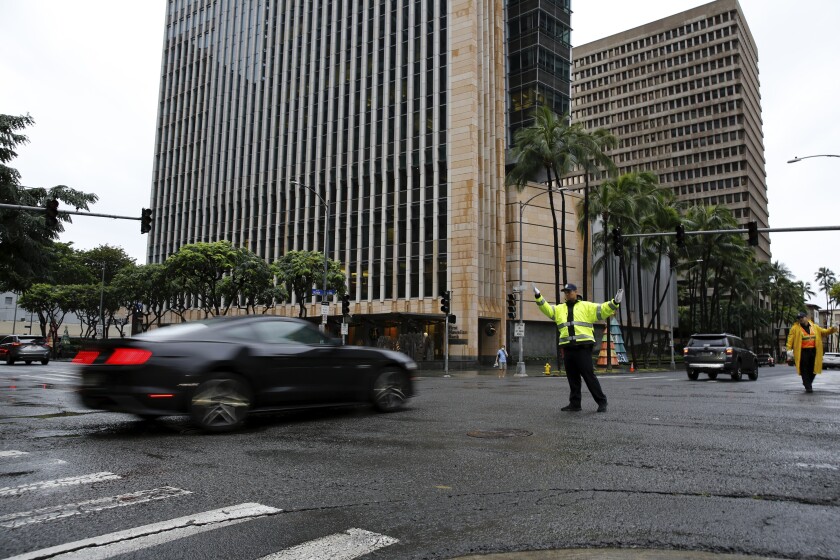 A police officer directs traffic during a power outage in downtown Honolulu after a severe winter storm swept the islands, Tuesday, Dec. 7, 2021. (AP Photo/Caleb Jones)