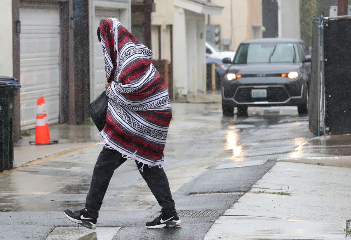 Light rain falls on the Newport Peninsula where a man wraps himself in a blanket on Thursday afternoon.
