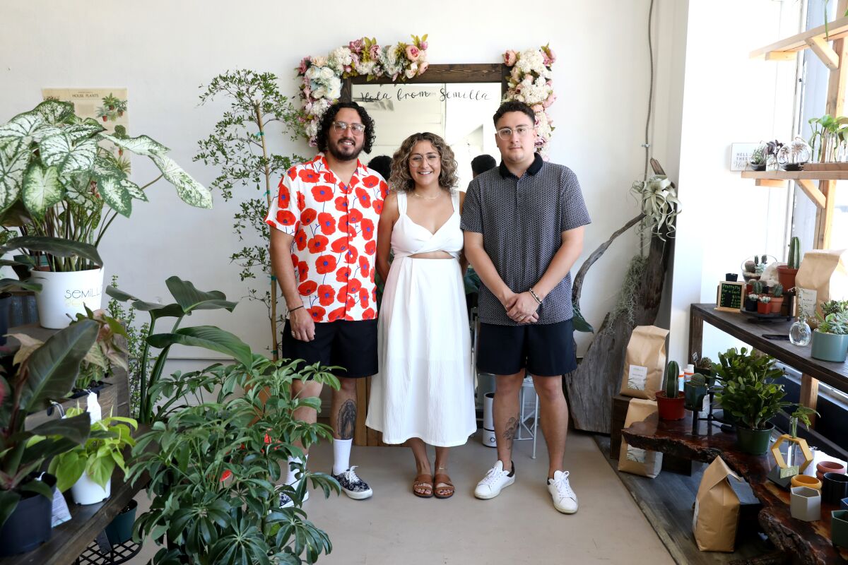 Three people stand inside a plant shop 