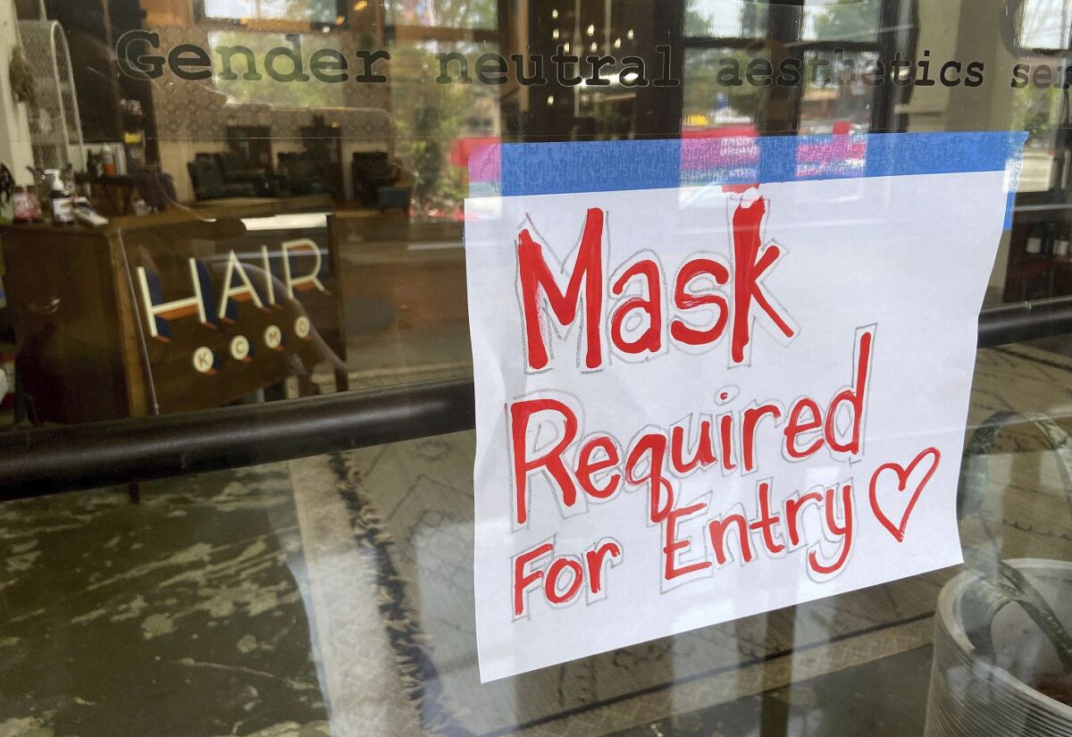 FILE - This July 28, 2021 file photo shows a sign on the door of a hair salon informing patrons that masks are required to be in the business in Kansas City, Mo. Businesses large and small are reinstituting mask mandates and requiring vaccines of their customers as U.S. coronavirus cases rise. (Jill Toyoshiba/The Kansas City Star via AP, File)