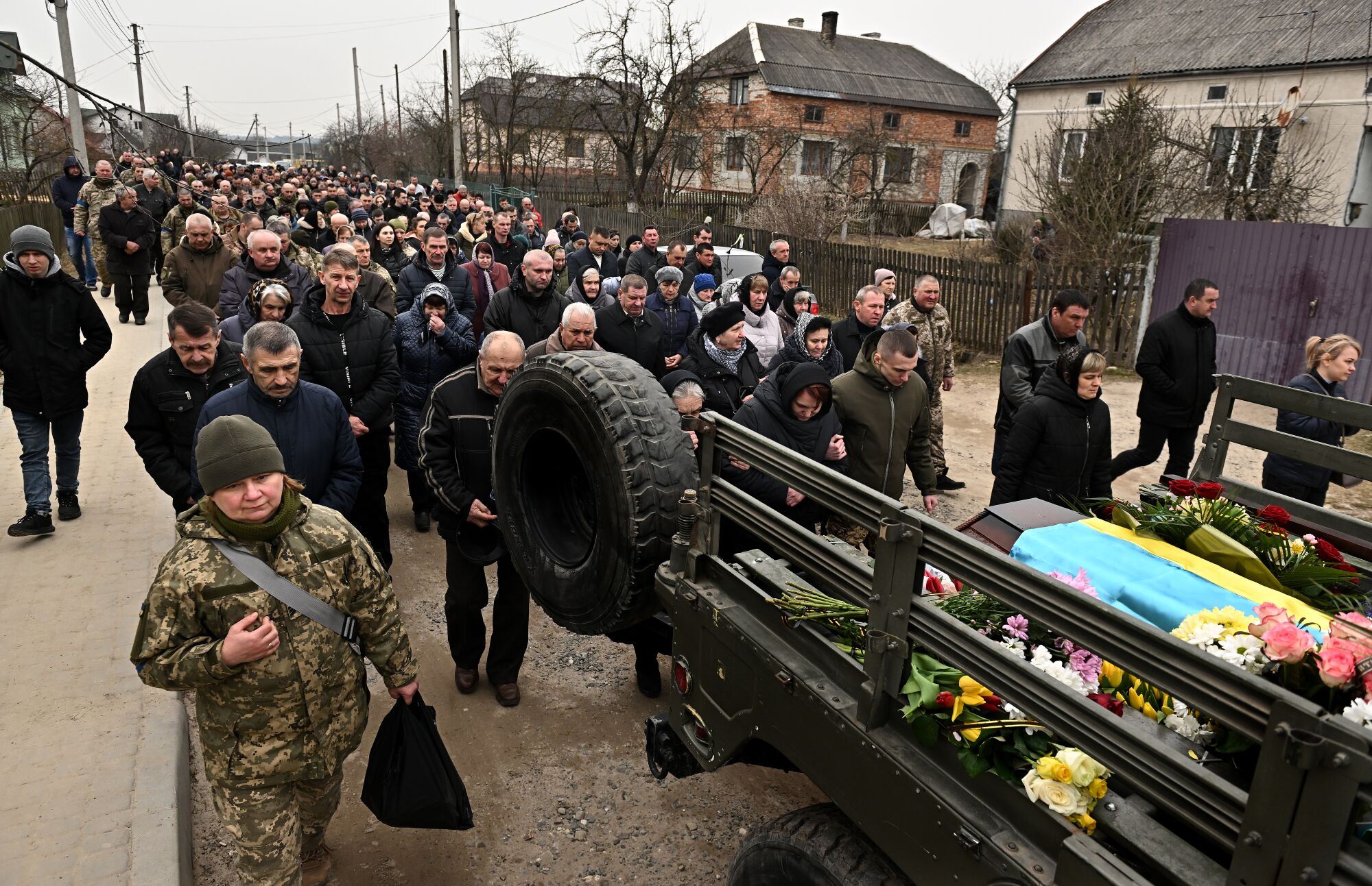 A funeral procession carrying the casket of two Ukrainian soldiers makes its way through the streets of Starychi, Ukraine.