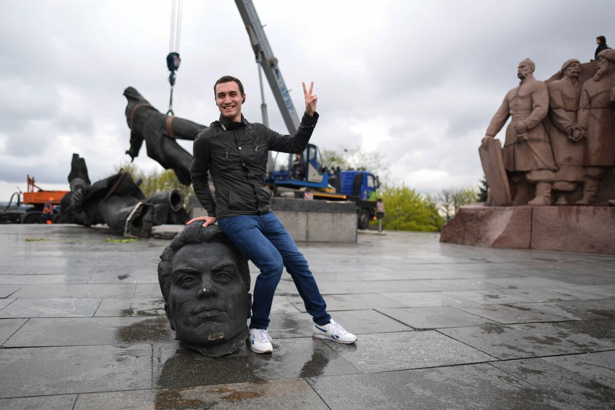 A man poses by the bronze head of a Soviet-era monument dismantled in Kyiv, Ukraine, in April 2022. 