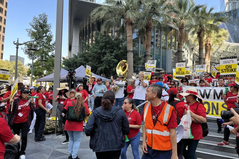 A band plays instruments among a crowd of people in red shirts