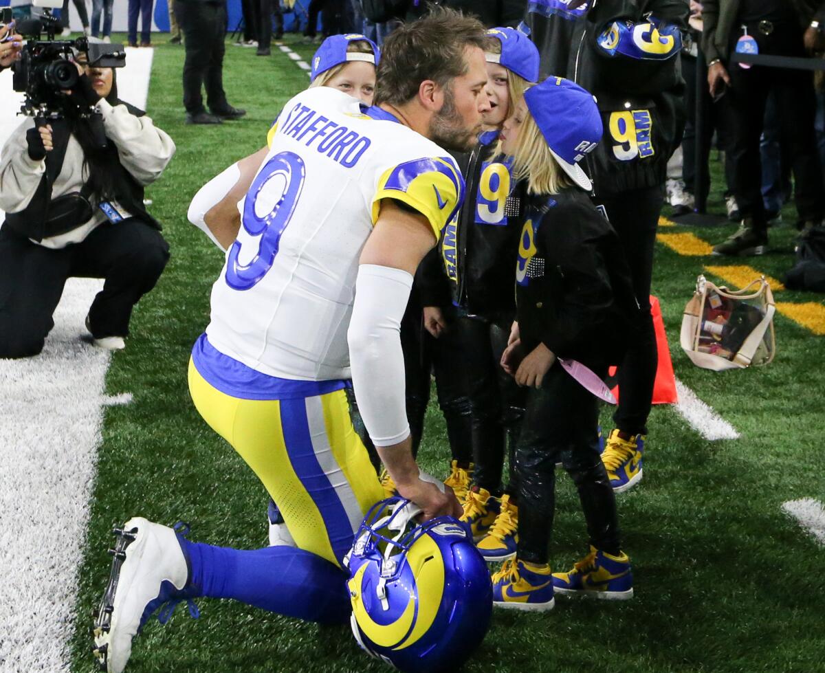 Matthew Stafford kneels to talk to his children before a game.
