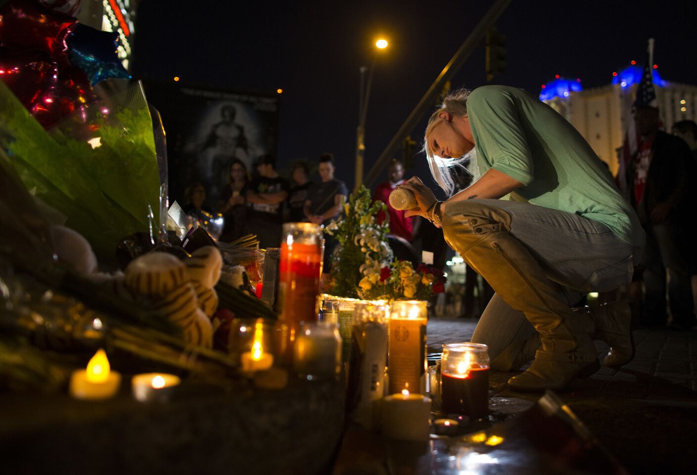 Kaili Berdge of Scottsdale, Ariz. makes sure every candle stays lit at a memorial for the victims of the mass shooting near the crime scene .