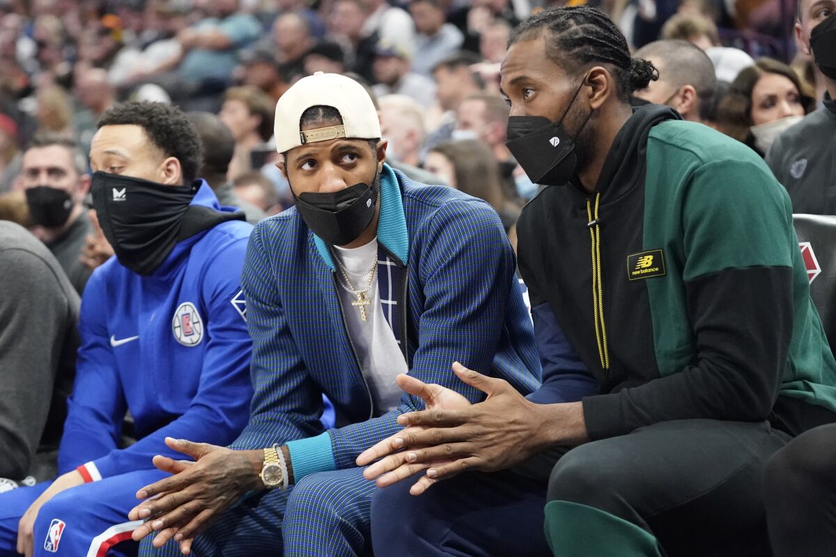 Los Angeles Clippers' Paul George and Kawhi Leonard look on from the bench.
