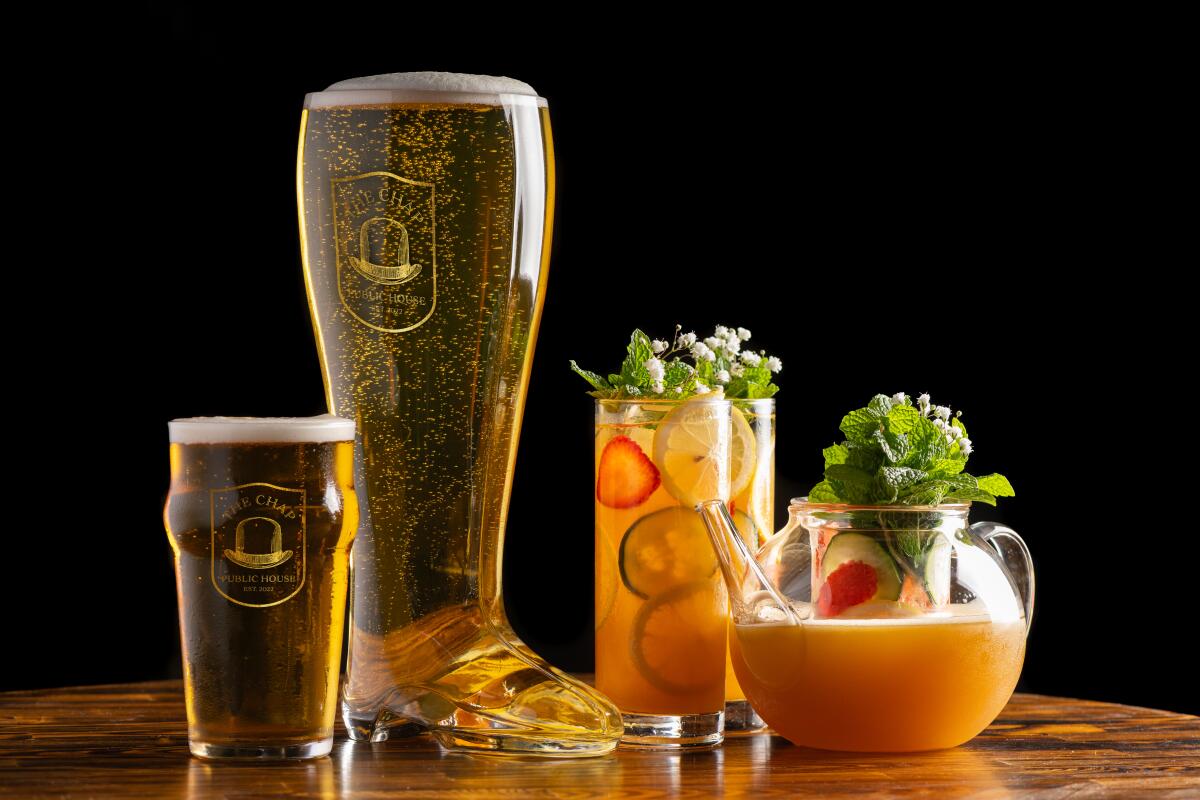 A pint of beer, a tall glass boot of beer, and Pimm's cups decorated with strawberries, cucumbers, lemon slices and mint.