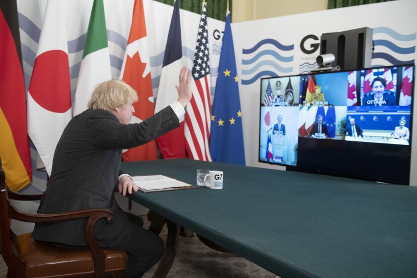 Britian's Prime Minister Boris Johnson waves as he hosts a virtual meeting of G7 leaders, from within the Cabinet Room at Downing Street in London, Friday Feb. 19, 2021. Johnson is chairing a virtual meeting Friday with leaders of the Group of Seven economic powers, holding their first meeting of 2021. (Geoff Pugh/Pool via AP)