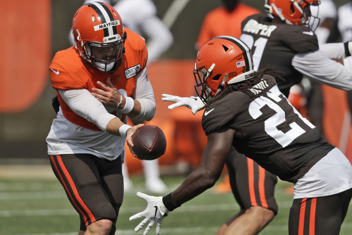 Cleveland Browns quarterback Baker Mayfield, left, hands the ball off to running back Kareem Hunt during practice at the NFL football team's training camp facility, Thursday, Aug. 27, 2020, in Berea, Ohio. (AP Photo/Tony Dejak)