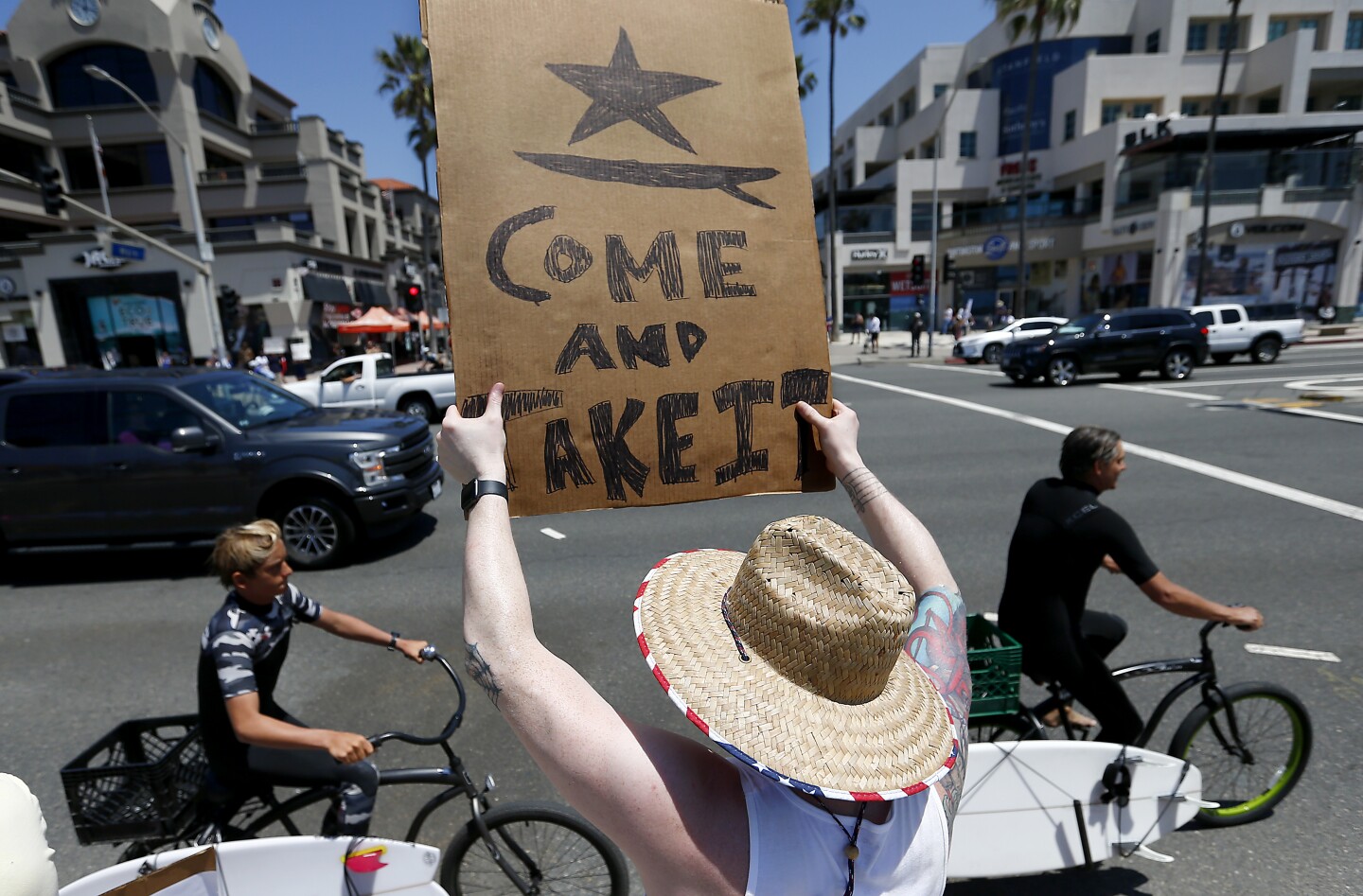 HUNTINGTON BEACH - MAY 2, 2020. Huntington Beach resident Kyle Richardson, 35, holds a sign telling California Gov. Gavin Newson to lift stay-at-home orders and reopen beaches, parks and the California economy, during a protest near the Huntington Beach Pier on Saturday, May 2, 2020. Responding to public pressure in recent days, Newson has implied that a gradual reopening following the coronavirus lockdown could begin as early as next week. (Luis Sinco/Los Angeles Times)
