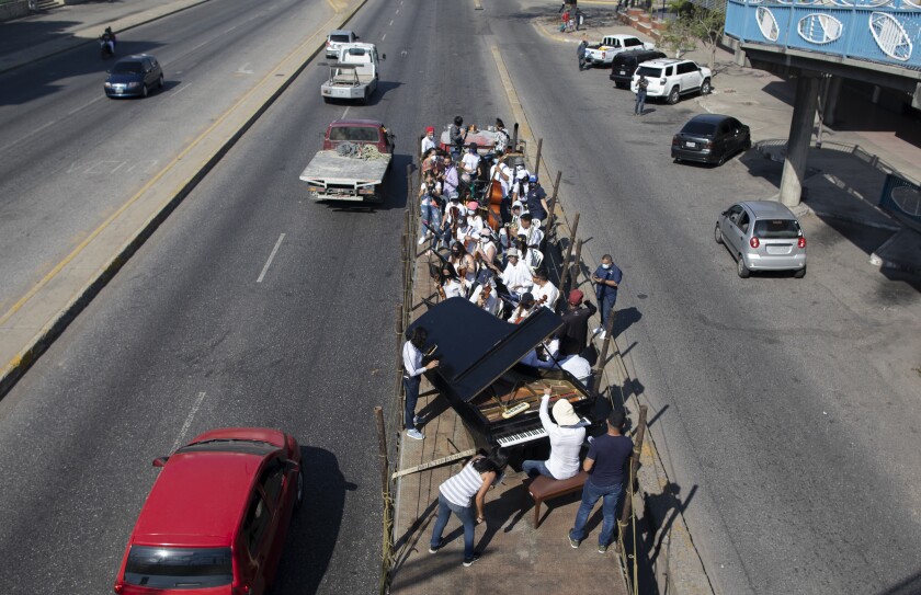 Musicians join pianist, composer and conductor Jose Agustin Sanchez on the bed of an 18-wheeler truck for a musical tour coined a "musical disinfection" in Barquisimeto, Venezuela, Thursday, March 4, 2021. Sanchez, who last year started playing what he calls his "Musical Vaccine" for COVID patients, is now joined by other musicians as they ride through the city playing his original compositions for anybody that wants to listen. (AP Photo/Ariana Cubillos)