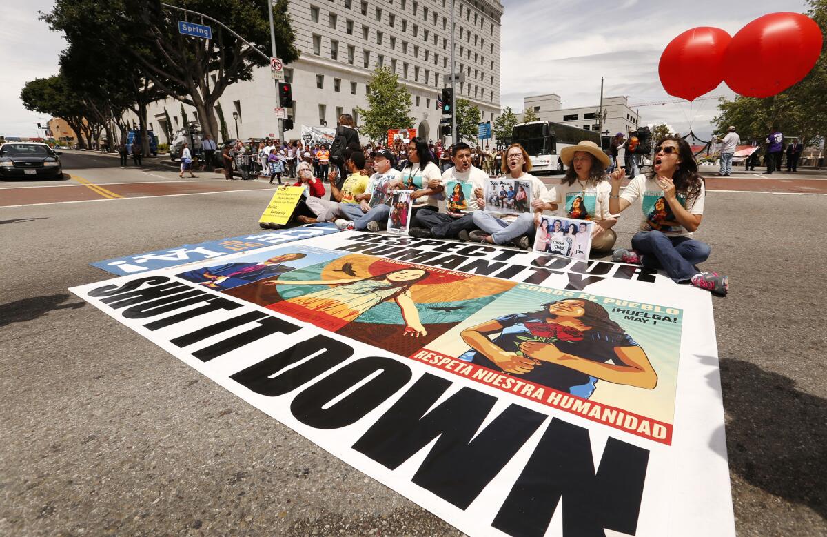 Protesters take a seat on Spring Street at Temple in downtown Los Angeles as part of the "Caravan Against Fear."