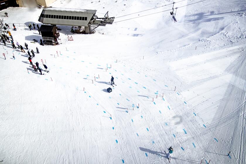 Blue dye in the snow marks social distancing guidelines in a lift line as seen from a gondola at Mammoth Mountain.
