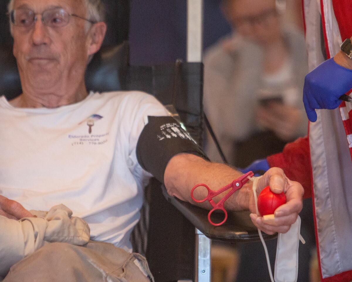 A donor squeezes a ball while getting blood drawn.