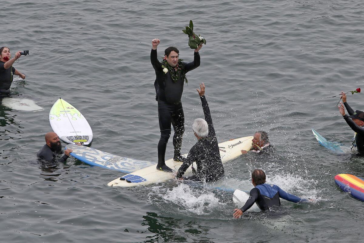 Ricky Fignetti, center, stands in the center of a circle during a paddle out for his father  on Saturday morning.