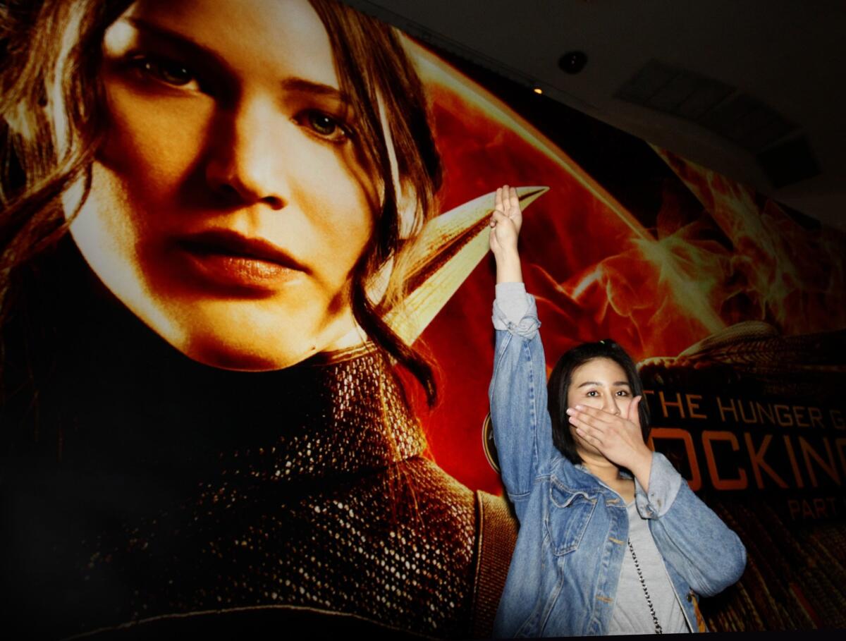 Nachacha Kongudom, 21, raises a three-finger salute outside a Bangkok cinema where "The Hunger Games: Mockingjay - Part 1" was shown Nov. 20.