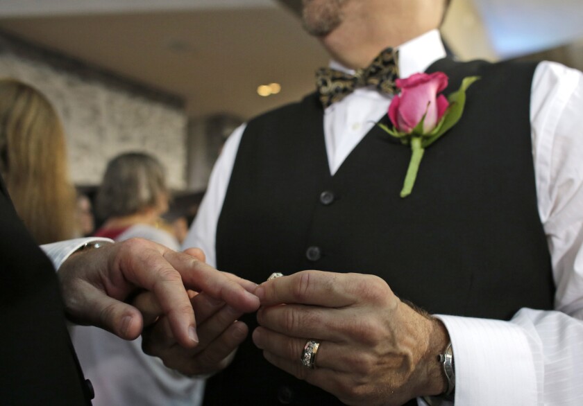 Steve Visano, 54, places a ring on his partner's hand during a group wedding ceremony in Fort Lauderdale, Fla. Republican presidential hopefuls have been asked whether they would attend a gay wedding. Some said they would, some not; still others avoided a direct reply.
