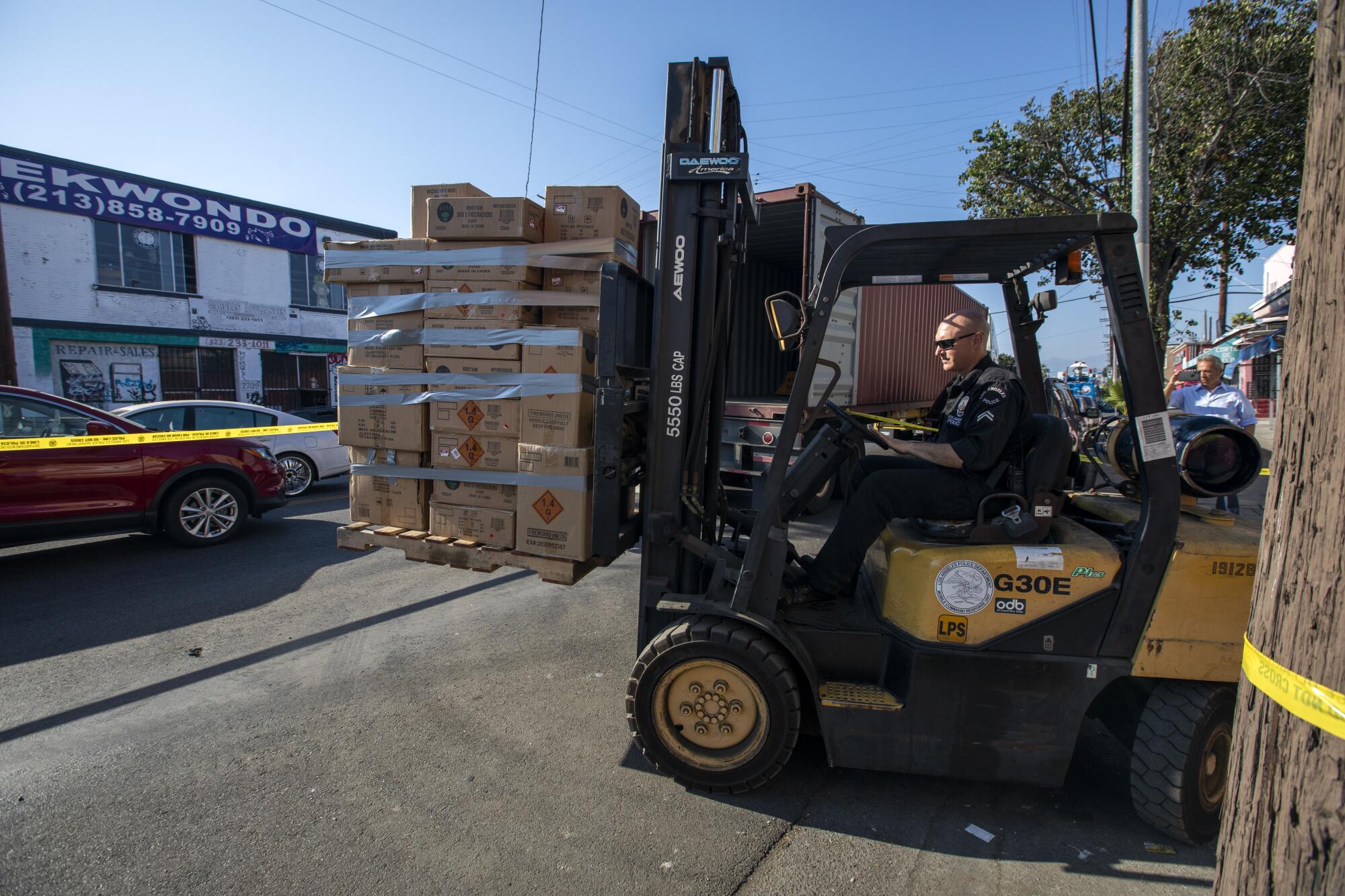 A person uses a forklift to lift cardboard boxes.