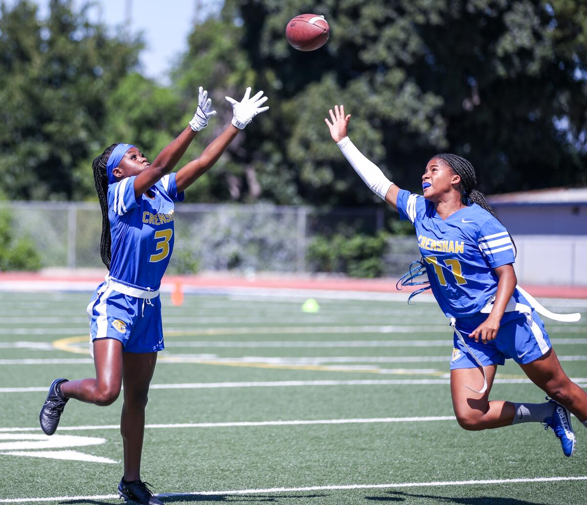 Crenshaw's Alani Anderson (left) and Talita Robinson go all out trying to make an interception.
