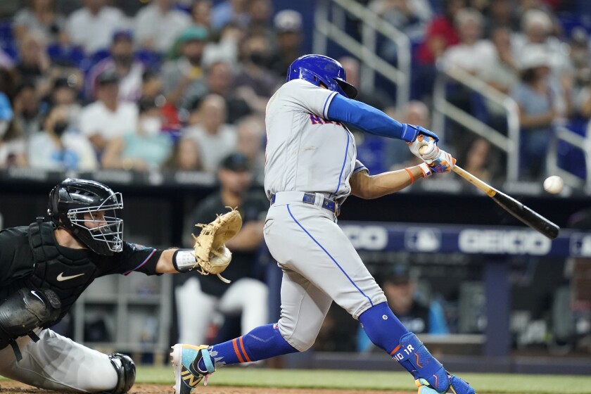 New York Mets' Francisco Lindor hits a three-run double during the sixth inning of the team's baseball game against the Miami Marlins, Friday, June 24, 2022, in Miami. At left is Marlins catcher Jacob Stallings. (AP Photo/Lynne Sladky)