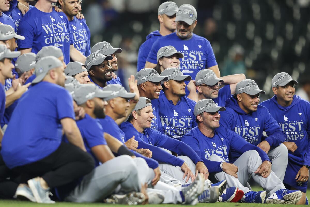 Dodgers players celebrate and pose for a team photo after clinching the NL West title in a victory over the Seattle Mariners.