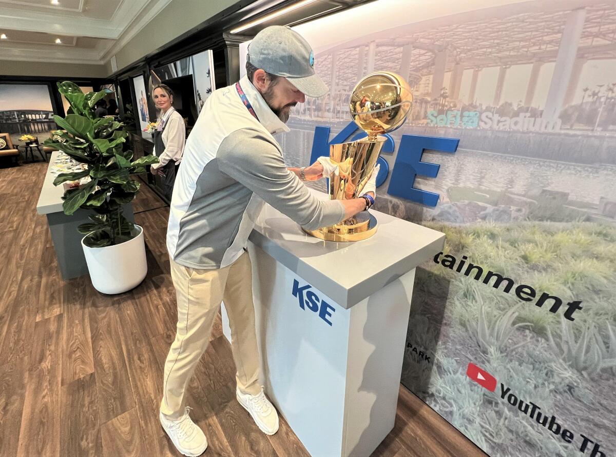 Josh Kroenke places the Larry O'Brien Championship Trophy on a pedestal at the U.S. Open.