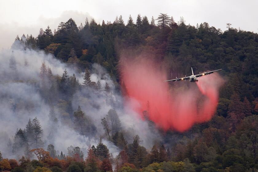 In this Sept. 15, 2015, file photo, a plane drops a load of fire retardant over a smoldering hillside in Middletown, Calif. Thanks to El Niño rains, the risk of wildfires has diminished.