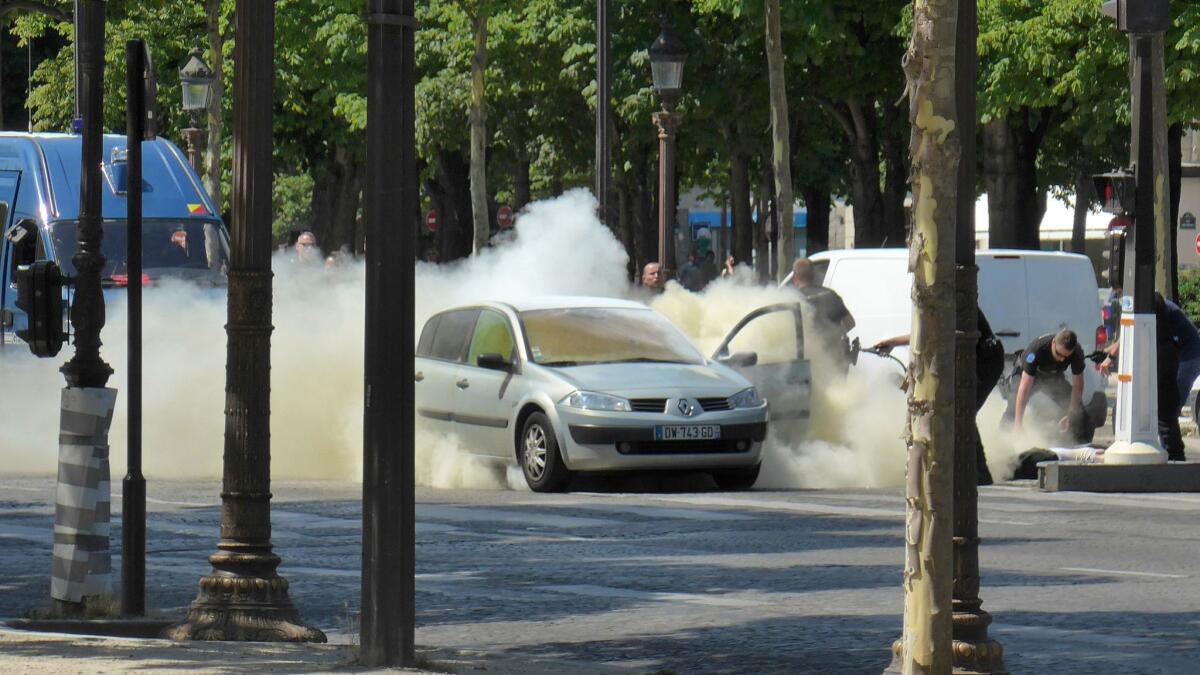 French gendarmes use fire extinguishers after a man rammed into a police convoy and detonated an explosive device Monday on the Champs Elysees in Paris.