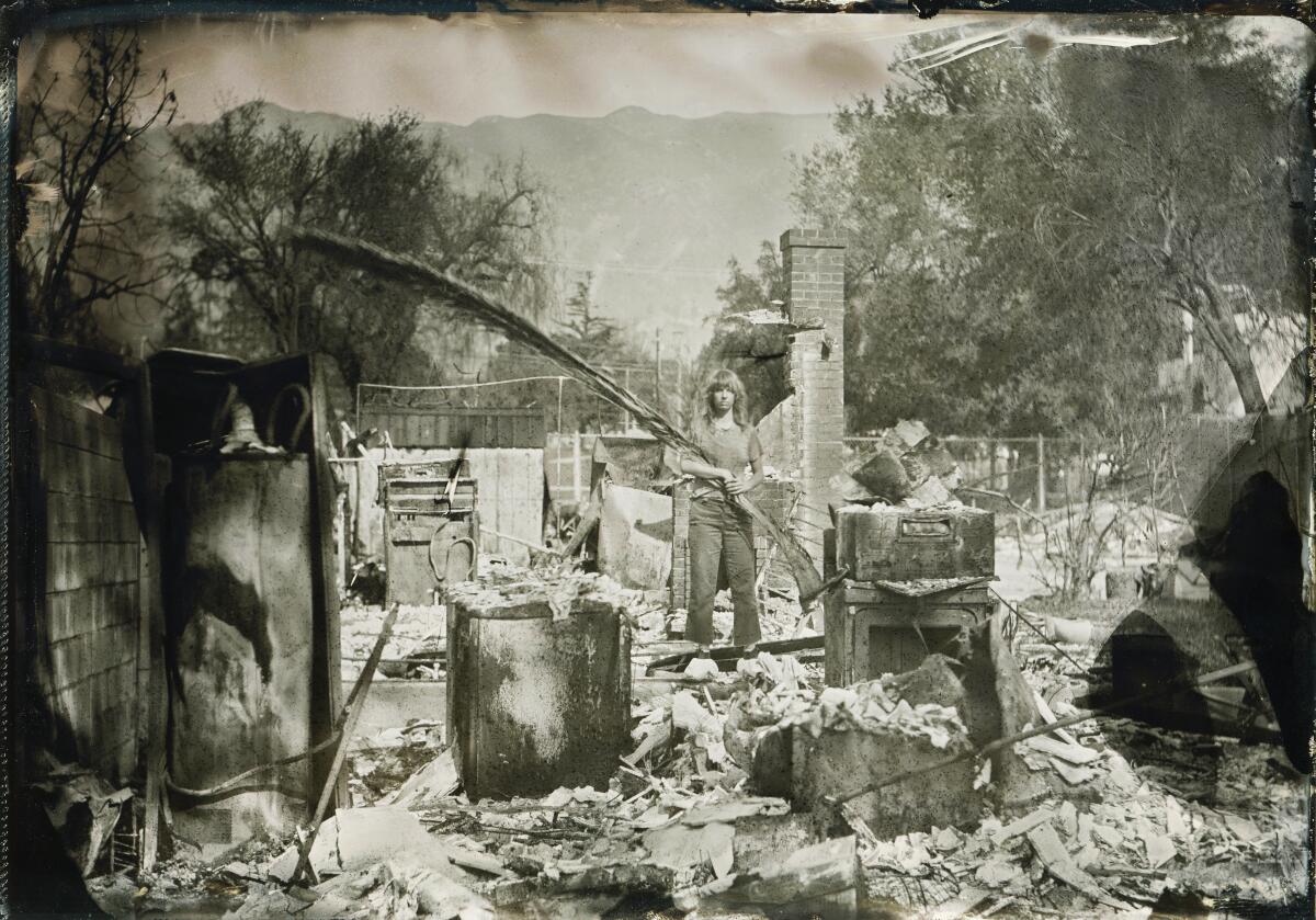 A woman holds a palm frond while standing in rubble.