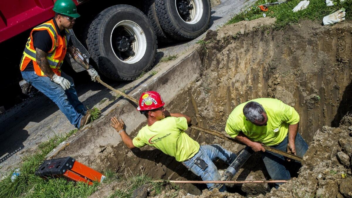 Workers replace lead-tainted pipes in Flint, Mich., in 2016.