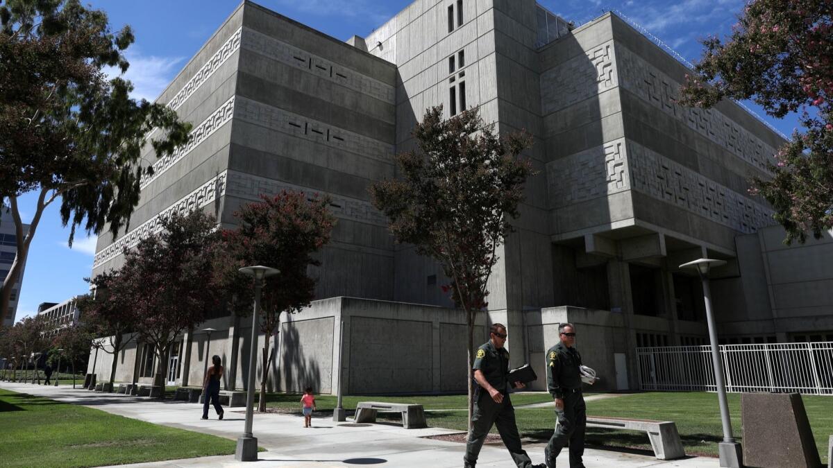 Orange County sheriff's deputies walk past the county jail in Santa Ana. The county's Board of Supervisors has voted to extend a contract with a vendor responsible for improperly recording attorney-inmate phone calls in the facility.