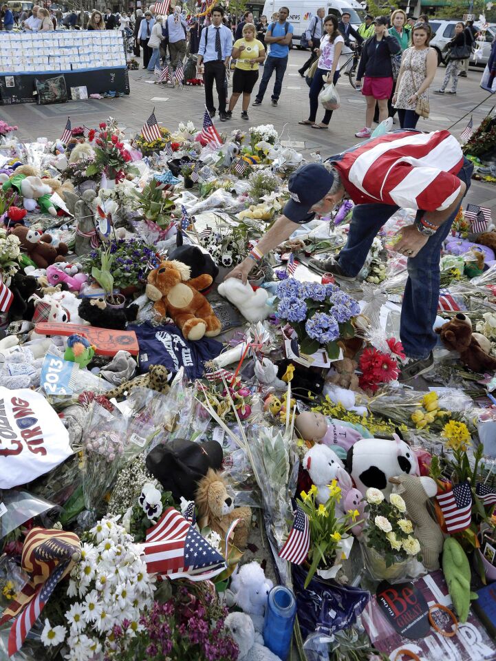 Kevin Brown of Boston, right, places a teddy bear at a makeshift memorial to the victims of the April 15 bombings near the Boston Marathon finish line, in a May 7, 2013, image.