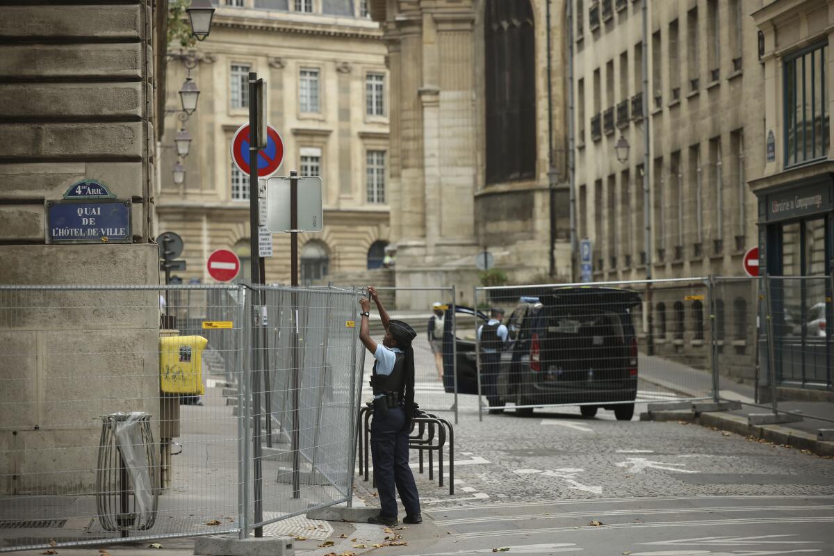A police officer sets up fences in a Paris street.