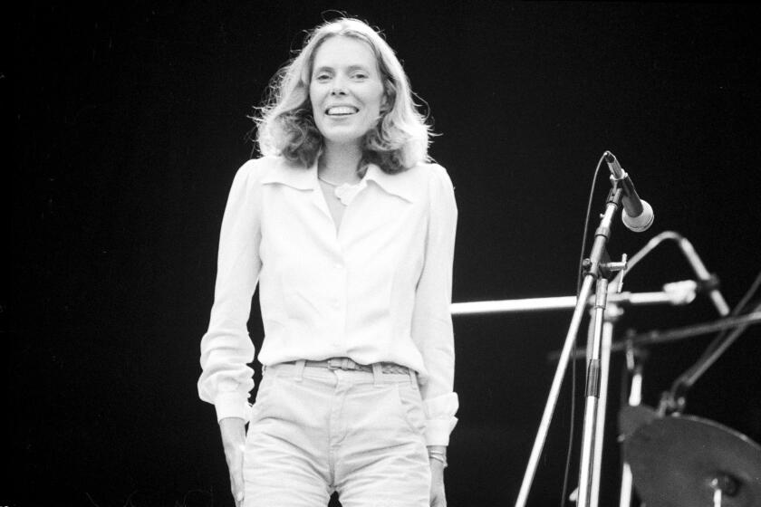 A black and white image of a woman standing onstage in front of a microphone