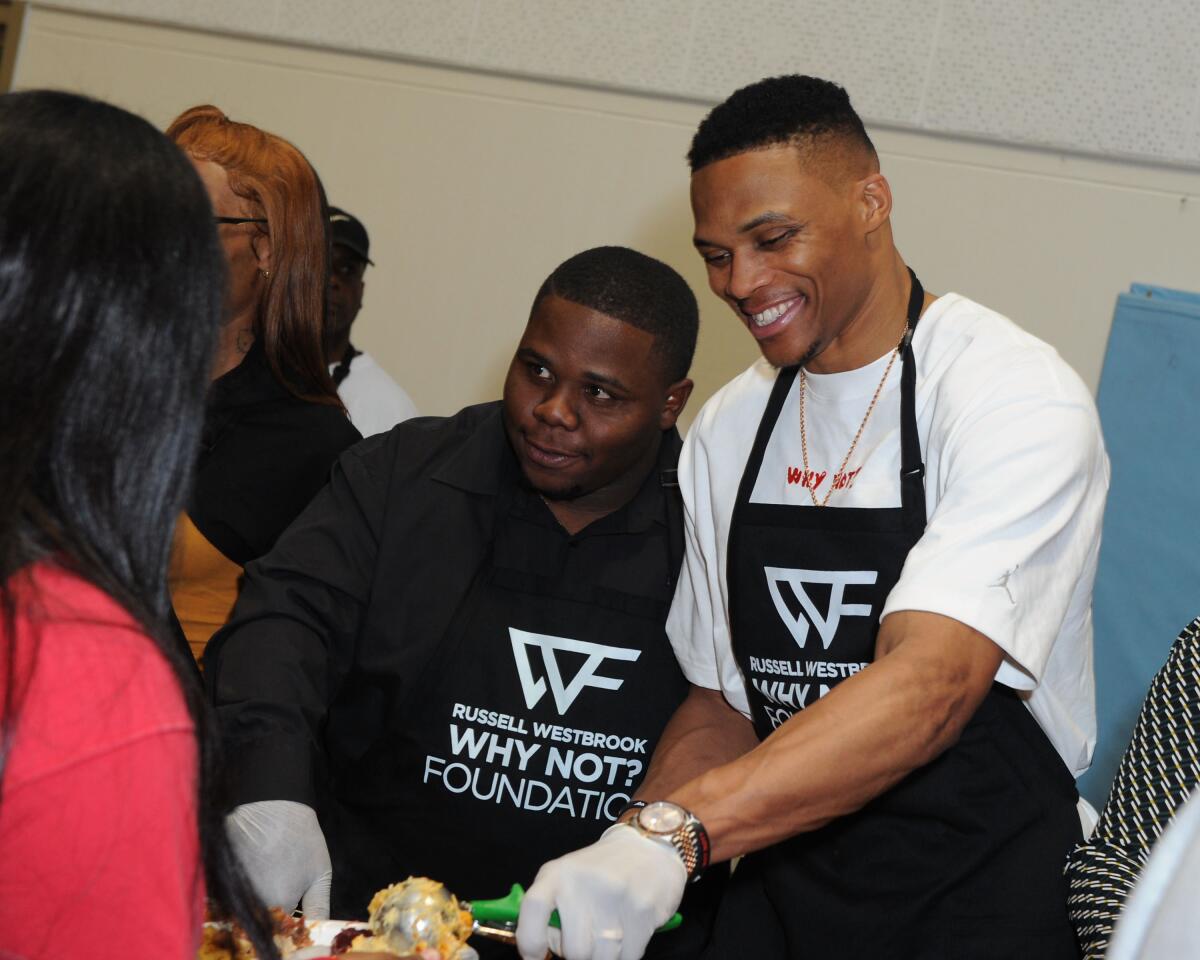 Russell Westbrook is joined by brother Raynard, left, while dishing an early Thanksgiving dinner at Jesse Owens Community Regional Park on Nov. 23.