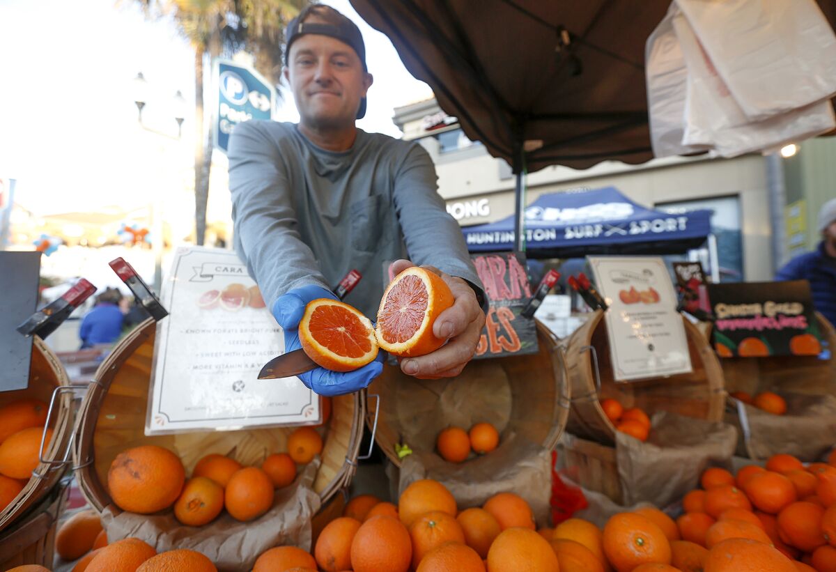 Mike Rosendahl shows a cara cara orange during the spring grand opening and celebration of Surf City Nights on Tuesday.