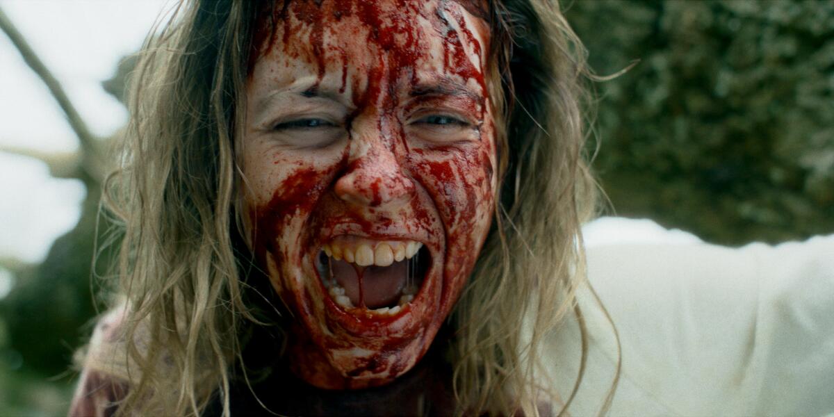 A woman screams with her face spattered in blood.
