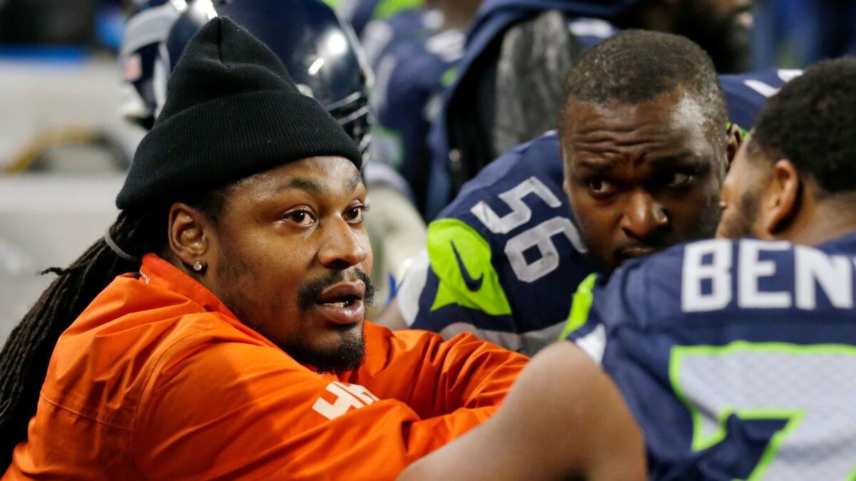 Then-retired running back Marshawn Lynch, left, chats with former teammates on the Seattle Seahawks sideline on Dec. 4.