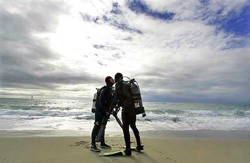 A KISS BEFORE DRYING: Jennifer and Erik Nelson of Lomita share a moment under an approaching storm last week after diving off Redondo Beach.