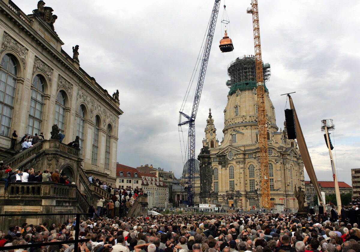 By using a special crane, workers raise the cupola and gilded cross on Dresden's Frauenkirche, or Church of Our Lady, in June 2004.