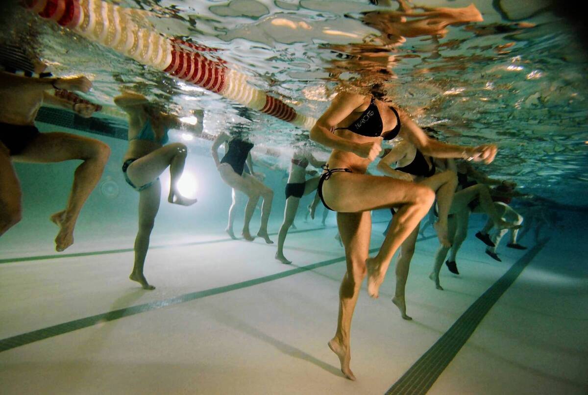Swimmers follow the movements of instructor Fabian Rodriguez on the pool deck at an aqua kickboxing class at Equinox Palos Verdes.