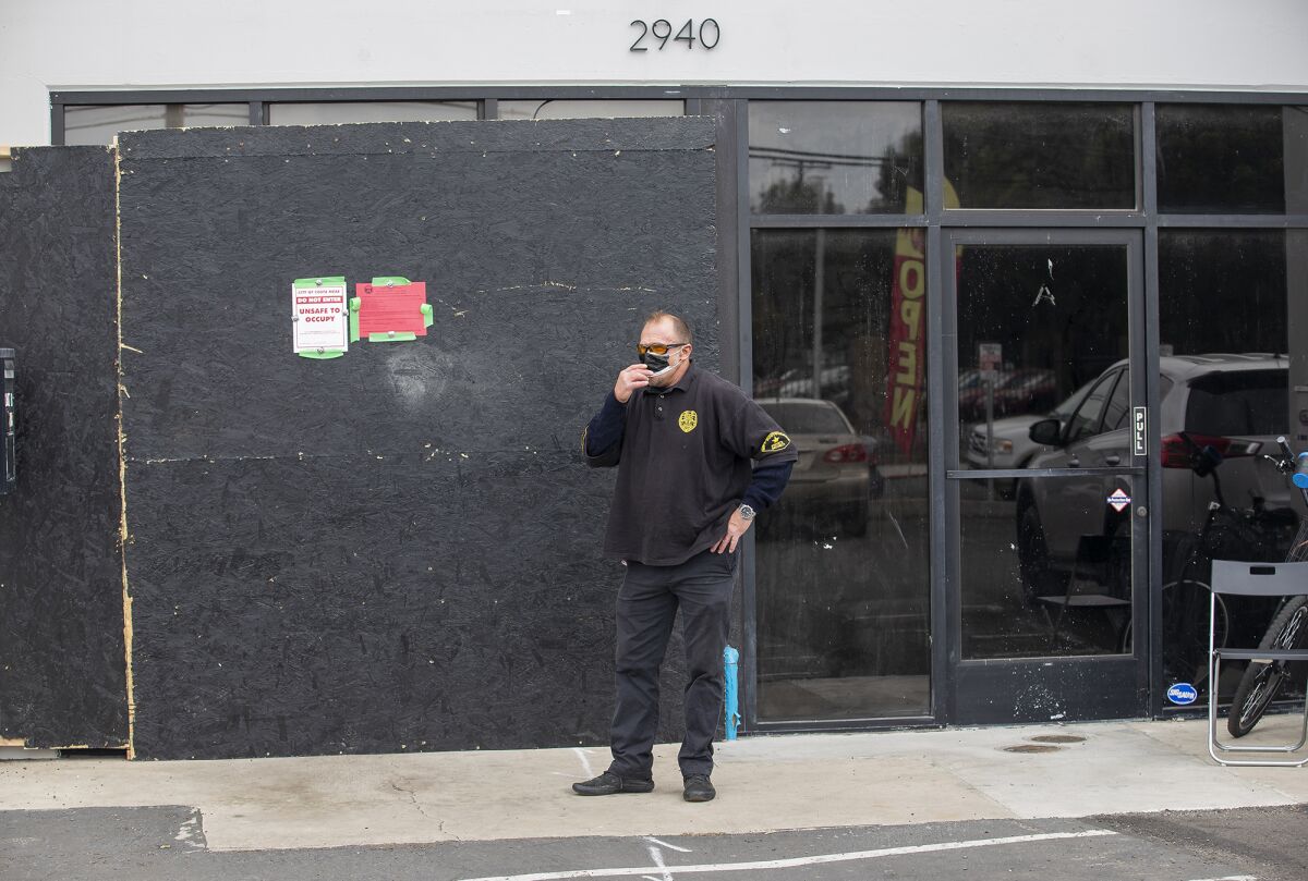 A guard stands outside an illegal dispensary at 2940 College Ave. in Costa Mesa raided by the Bureau of Cannabis Control.