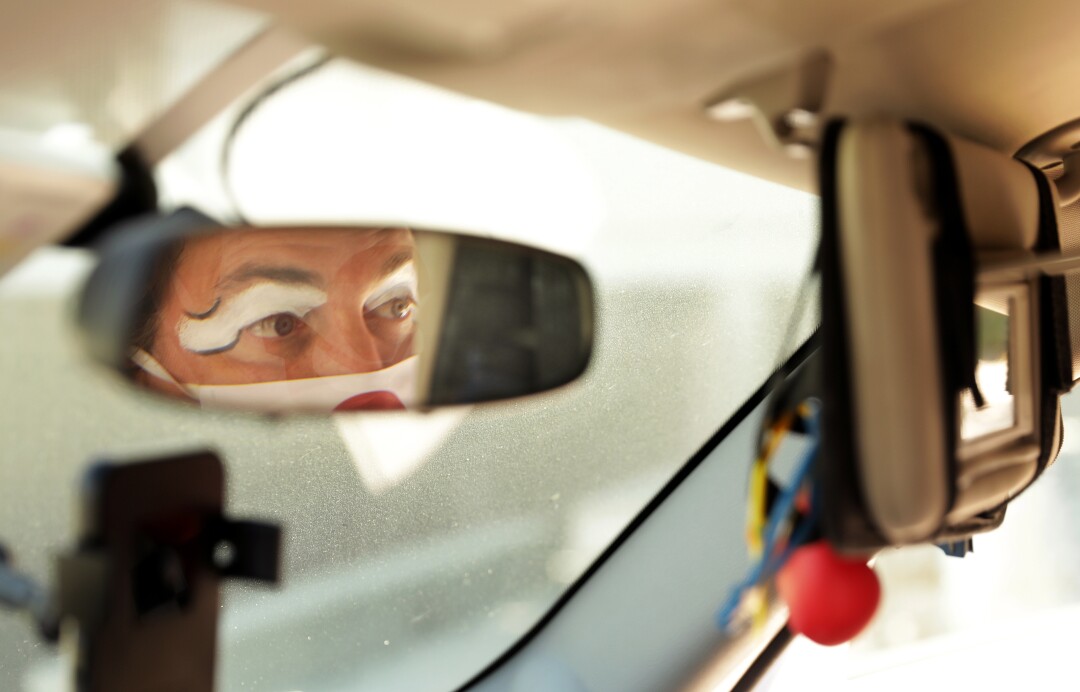 Guilford Adams checks his makeup in the car before performing a show for children at a preschool in Glendale.