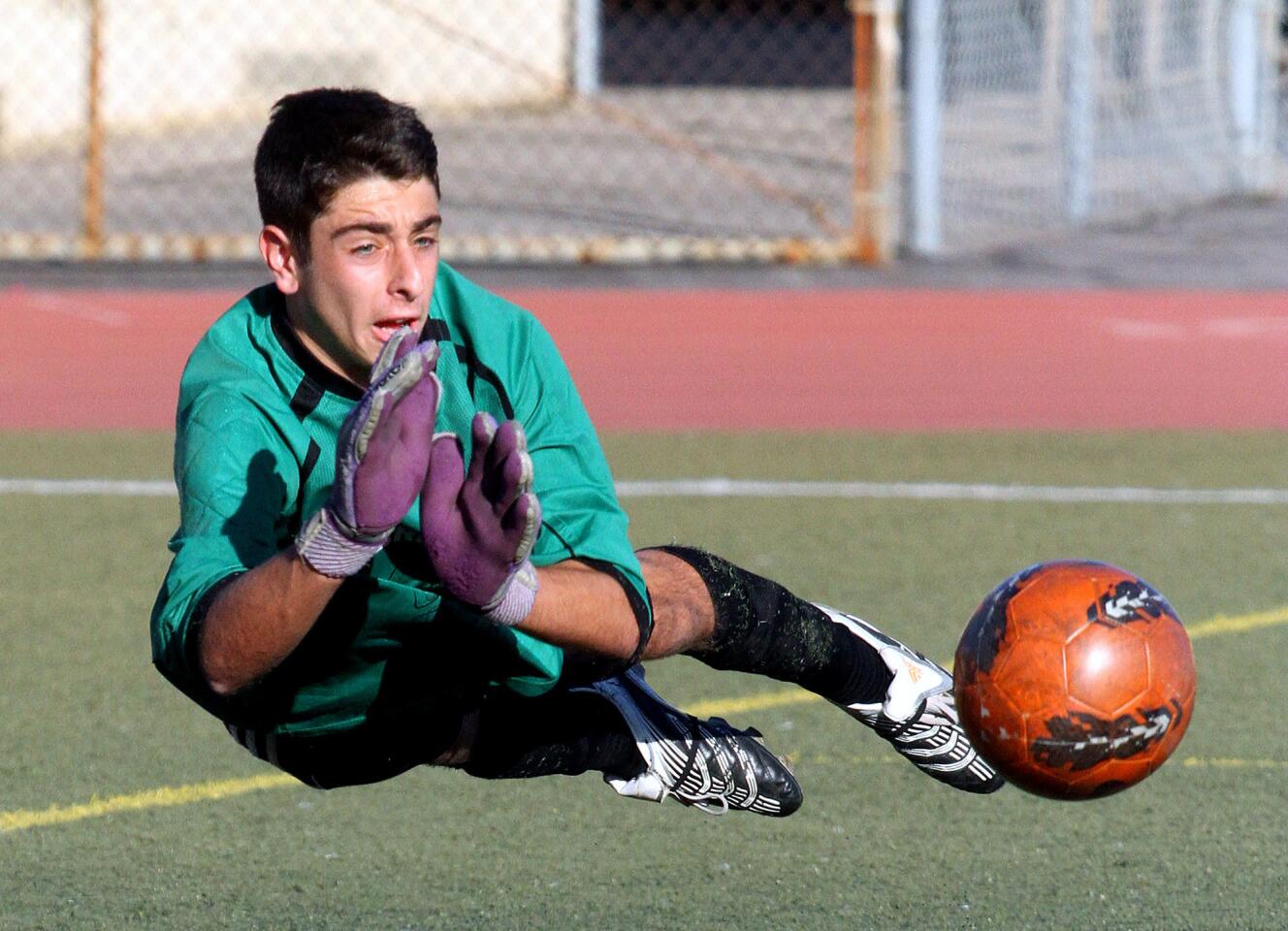 Hoover's keeper Emil Ohanyan dives to keep the ball from scoring off of a Glendale shot in a Pacific League boys soccer game at Glendale High School on Thursday, February 13, 2014.