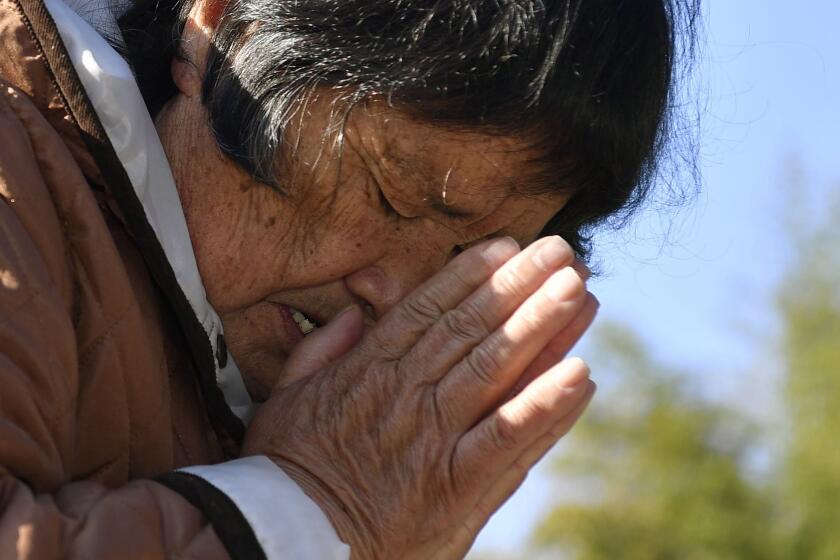 A woman who lost her husband and grandchild in the 2011 earthquake and tsunami, prays in front of the grave in Miyako, Iwate prefecture, Japan Thursday, March 11, 2021. Thursday marks the 10th anniversary of the massive earthquake, tsunami and nuclear disaster that struck Japan's northeastern coast. (Muneyuki Tomari/Kyodo News via AP)